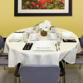 A beautifully arranged dining table with a white tablecloth and floral centerpiece in a cozy restaurant setting.