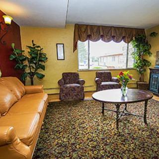 A cozy living room featuring a sofa, chairs, and a coffee table with decorative plants and a large window.