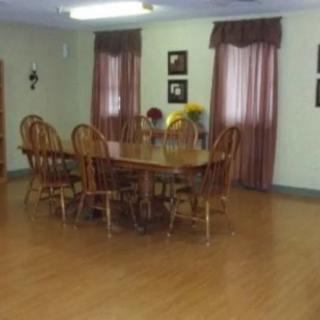 A dining room with a wooden table and chairs, featuring curtains and wall decor.