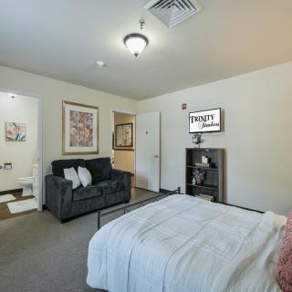 A modern bedroom with a bed, sofa, and artwork on the walls.
