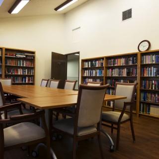 A well-organized meeting room with bookshelves, a large table, and multiple chairs.