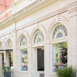 A charming brick storefront with arched windows on a sunny day.