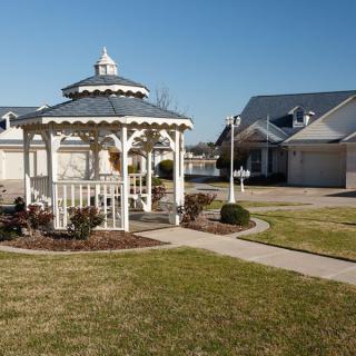 A suburban neighborhood with a white gazebo and houses in the background.