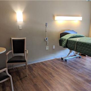 A modern hospital room with a bed, chair, and medical equipment.