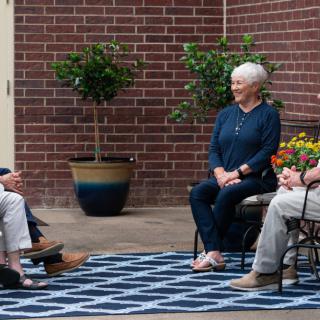 A group of people sitting outdoors having a conversation.