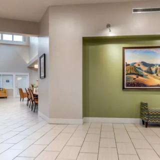 A spacious lobby with tiled flooring, featuring a seating area and a large framed artwork on a green accent wall.