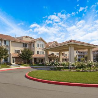 A residential building with landscaped surroundings and a covered driveway.