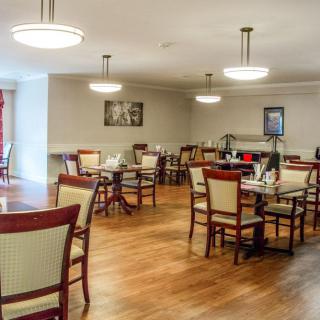 An empty dining room with neatly arranged tables and chairs on a wooden floor.
