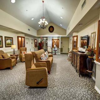 A cozy lounge area featuring comfortable seating, a chandelier, and decorative artwork on the walls.