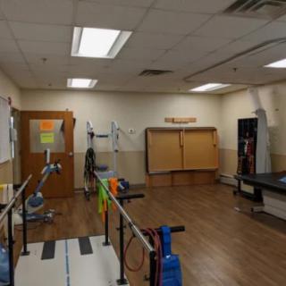 A spacious physical therapy room equipped with various exercise and rehabilitation equipment.