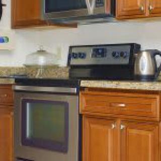 A cozy kitchen featuring wooden cabinets, a stainless steel oven and stove, a microwave, and a granite countertop.