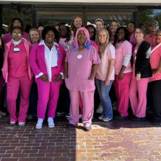 A group of people wearing pink uniforms standing together outside.
