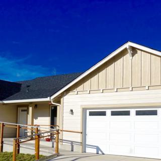 A modern house with a garage and sloped driveway under a clear blue sky.