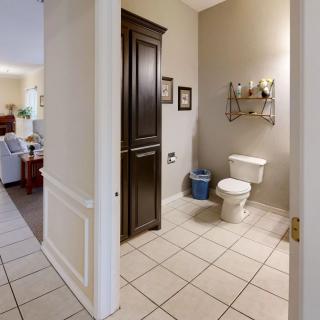 A view of a bathroom with a toilet, tile flooring, and a dark wooden cabinet.