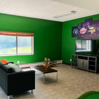 A modern living room with vibrant green walls, a comfortable couch, and a television.