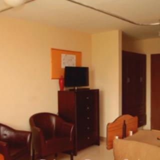 A cozy hotel room with a television, dresser, chairs, and a bed.