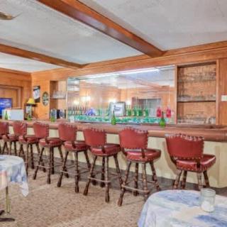 An interior view of a bar with multiple red stools lined up along the counter.