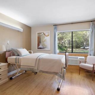 A clean and bright hospital room with a single bed and a large window.