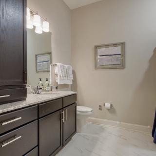 A modern bathroom featuring dark cabinetry, a large mirror, and stylish lighting.