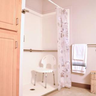 An accessible bathroom equipped with a shower chair and grab bars for safety.