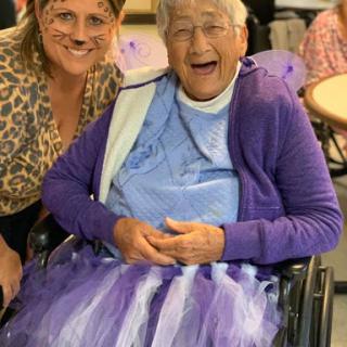 A joyful moment shared between a caregiver and an elderly woman enjoying a fun activity together.