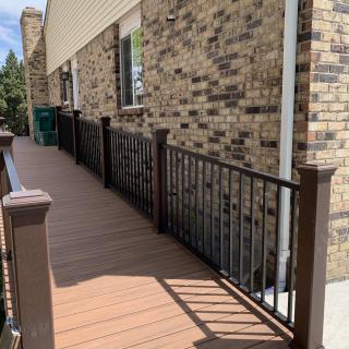 A wooden ramp with a railing alongside a brick building.