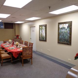 A conference room featuring a dining table set with decorations and surrounded by chairs, with framed artwork on the walls.