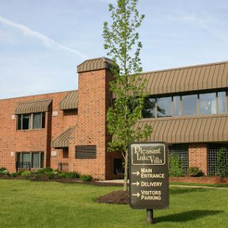 A modern brick office building with landscaped surroundings and a prominent sign.