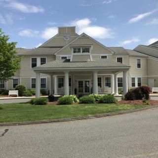 A large residential building with landscaped gardens and a driveway in front.