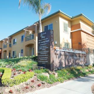 A well-maintained apartment building with lush landscaping under a clear blue sky.