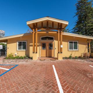 A yellow building with a pitched roof and parking spaces in front, set against a clear blue sky.