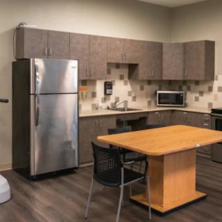 A modern kitchen interior with appliances and a central wooden table.
