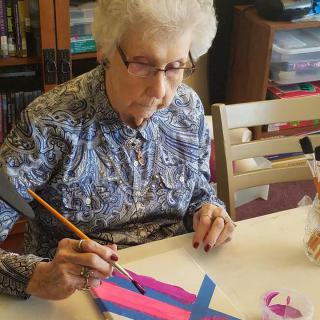 An elderly woman engaged in painting as a creative hobby.