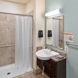 A clean and modern bathroom with a shower, sink, and mirror.