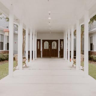 A serene walkway leading to the entrance, framed by elegant columns.