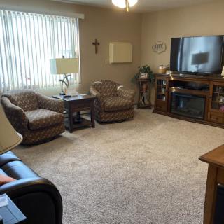 A cozy living room featuring armchairs, a sofa, a large TV, and various decorative elements.