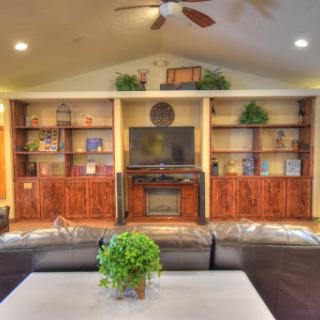 A cozy living room featuring an entertainment center, bookshelves, and modern furnishings.