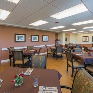 A well-lit dining area with neatly arranged tables and chairs, adorned with artwork on the walls.