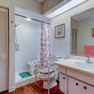 A cozy bathroom with a shower, sink, and toilet featuring floral decor.