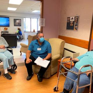 A healthcare professional engages with two patients in an assisted living setting.