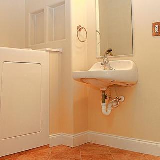 A bathroom with a wall-mounted sink and mirror, featuring a tiled floor.