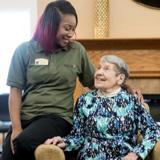 A caregiver and an elderly woman sharing a joyful moment together.