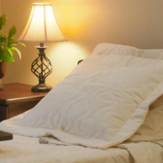 A cozy bedroom with a softly lit lamp on the nightstand next to a neatly made bed.
