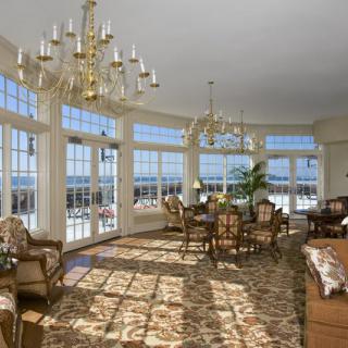 A luxurious living room with large windows and elegant chandeliers, filled with natural light.