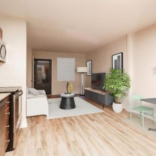 A modern living room with hardwood floors, featuring a sofa, coffee table, television, and indoor plant.