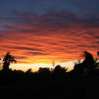 A vibrant sunset with orange and red clouds silhouetting the horizon.