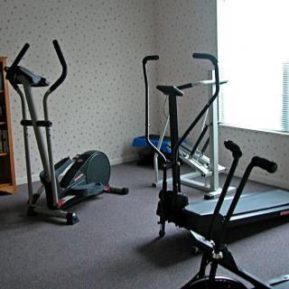 A home gym with exercise equipment including a treadmill and elliptical machines.