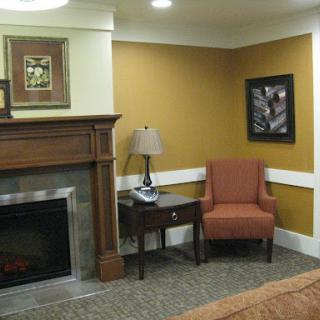 A cozy living room corner featuring an armchair, lamp, and a decorative fireplace.
