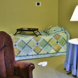 A cozy bedroom corner with a bed, patterned quilt, and a tray on top.