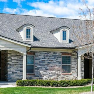 A modern residential house with a stone exterior and a well-maintained garden.